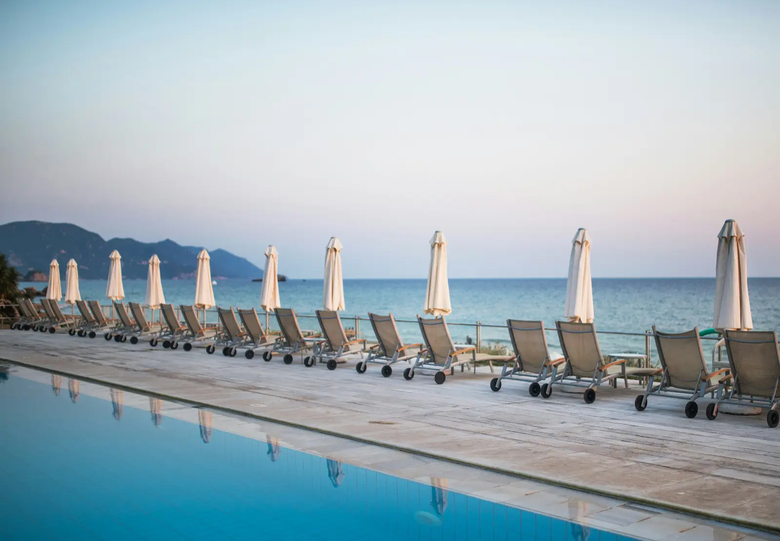 A resort poolside at dusk overlooking the sea